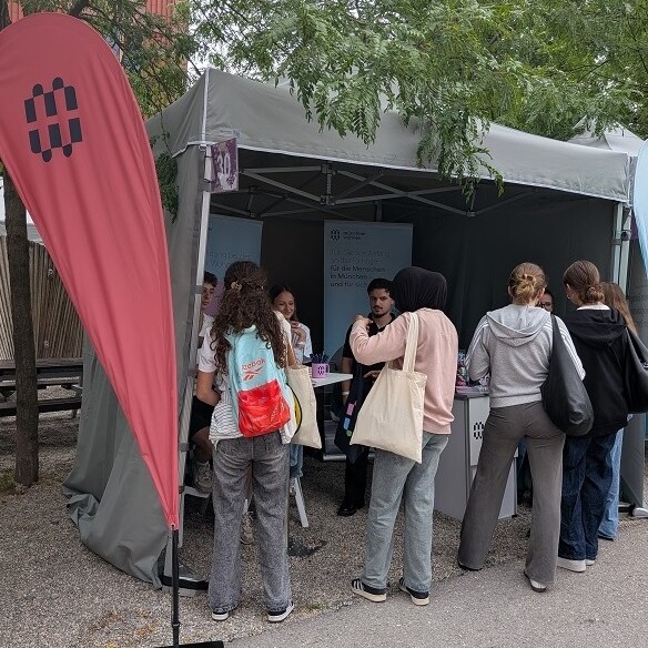 Blick auf den Stand der Münchner Wohnen an dem einige junge Menschen im Gespräch mit Mitarbeitern sind.