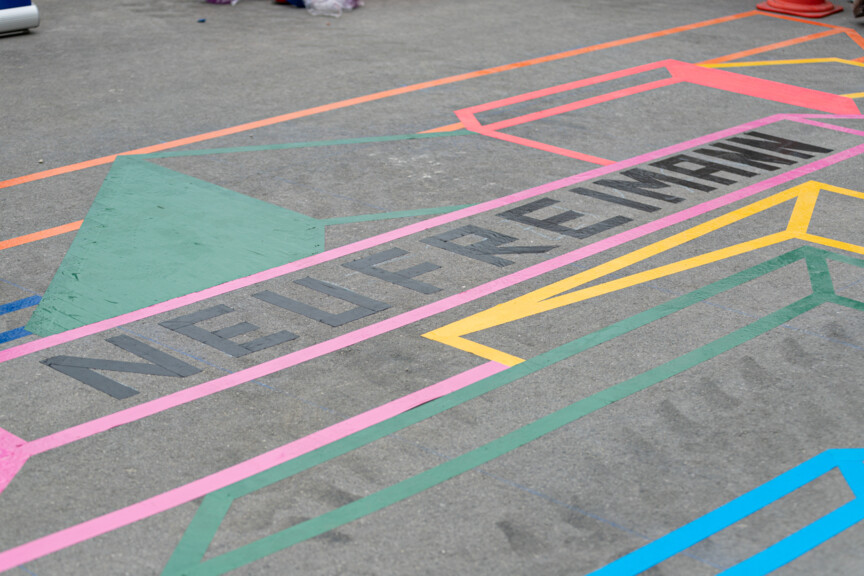 Auf grauem Asphaltboden steht in bunter Schrift das Wort Neufreimann geschrieben.