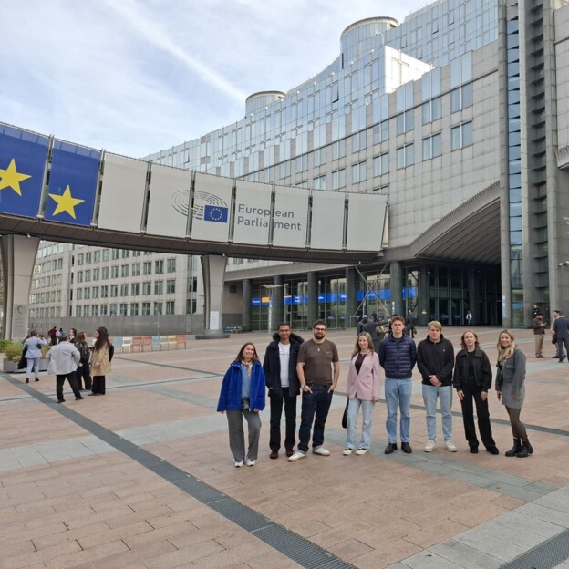 Eine Gruppe junger Menschen steht vor dem Gebäude des europäischen Parlaments.