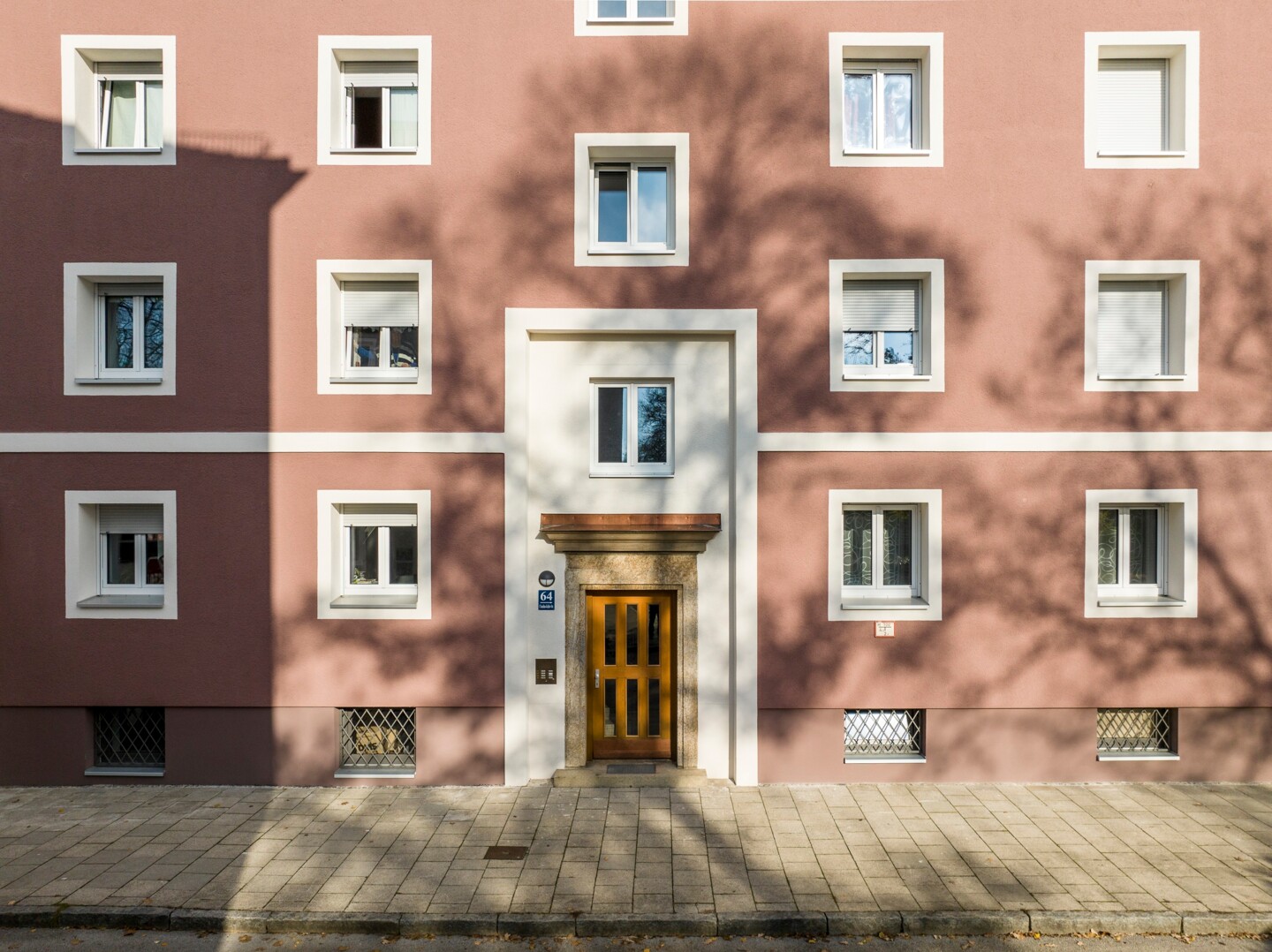 hellrote Hausfassade mit quadratischen weißen Fenstern.