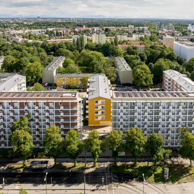 Drohnenaufnahme der fast fertigen Neubauten entlang der Zschokkestraße. Der mehrstöckige Gebäuderiegel ist u-förmig, in der Mitte sieht man eine etwas niedrigere Gebäudezeile. Drumherum sehr viel grüner Baumbestand.