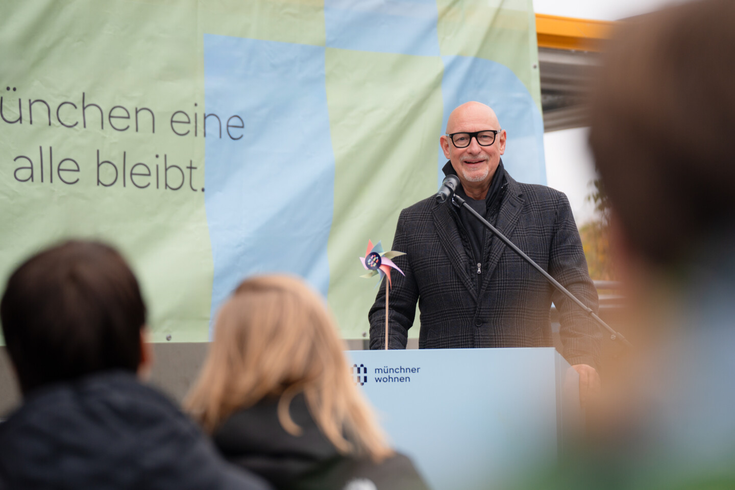 Jörg Franzen steht am Rednerpult, im hintergrund hängt ein Transparent mit dem Slogan der Münchner Wohnen "Damit München eine Stadt für alle bleibt".