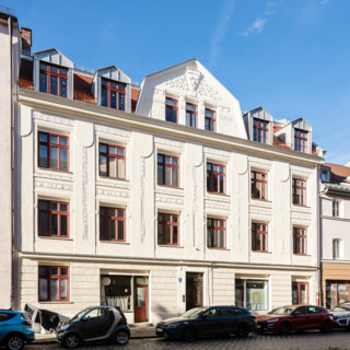 Blick auf eine reich dekorierte Jugendstilfassade. vor dem Haus stehen Autos auf der Straße.