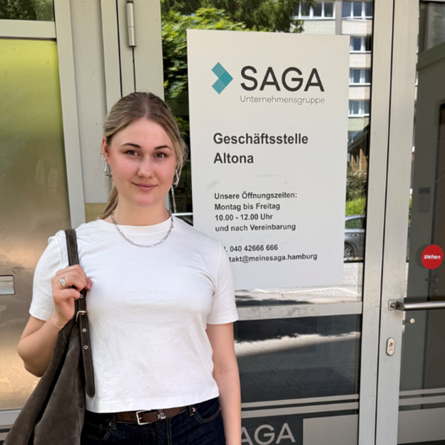 Eine junge Frau steht vor dem Eingang der SAGA Hamburg Geschäftsstelle.