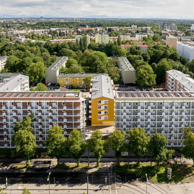 Drohnenaufnahme der Alten Heimat. Ein E-förmiges, mehrstöckiges Wohngebäude. In den Innenhöfen viele alte Bäume und Grünflächen.