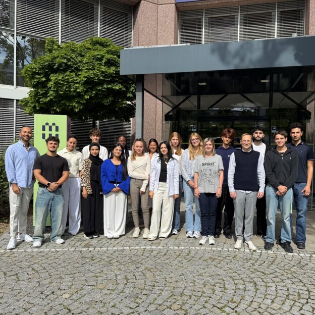 Gruppenbild der neuen Auszubildenden vor dem Haupteingang der Münchner Wohnen.