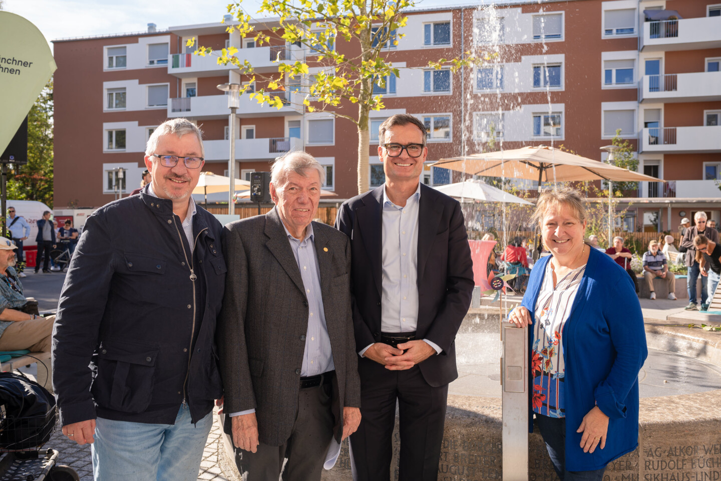 Vier Menschen stehen vor dem Brunnen und lächeln in die Kamera.