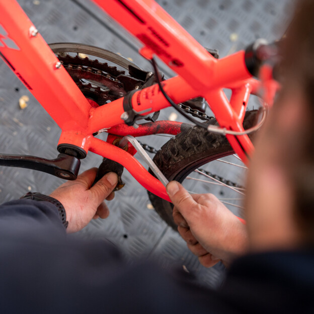 Nahaufnahme von zwei Händen, die gerade eine Fahrradkette reparieren.