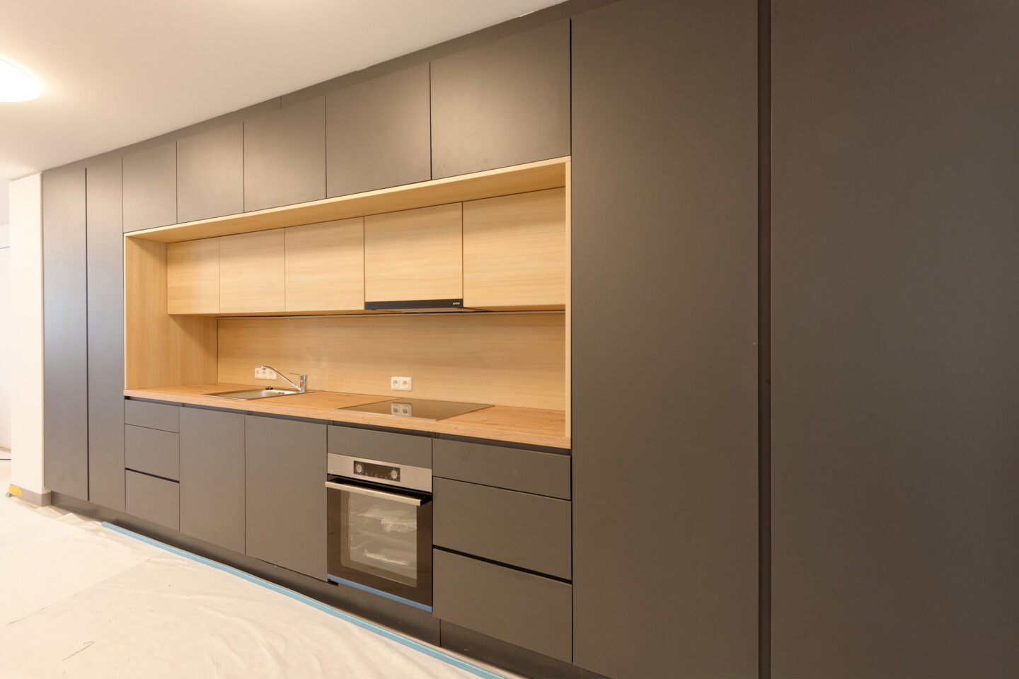 Blick auf die großzügige Küchenzeile im Gemeinschaftsraum des Azubiwohngebäudes. Neben viel Stauraum ist eine gut ausgestattete Küche zu sehen.