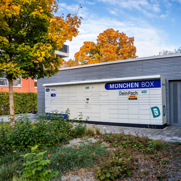 Aufnahme einer München Box Paketstation vor einem Wohnhaus. Viele Fächer unterschiedlicher Größe sind zu sehen.
