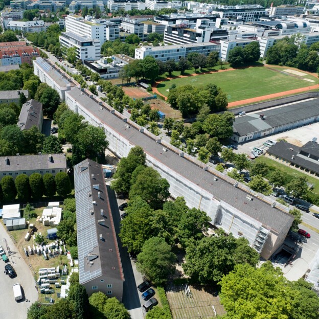 Drohnenaufnahme des tortenstückförmigen Grundstücks des Klimaquartiers. Die Häuserzeile am rand des Gebiets ist mit einem Baugerüst ummantelt.