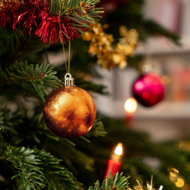 Nahaufnahme eines mit Kugeln und Lichtern geschmückten Tannenbaums.