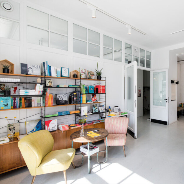 Innenansicht Shop Kinderkunsthaus Schwabing. Man sieht Regale voller Malutensilien und gemütliche Sessel zum Sitzen.