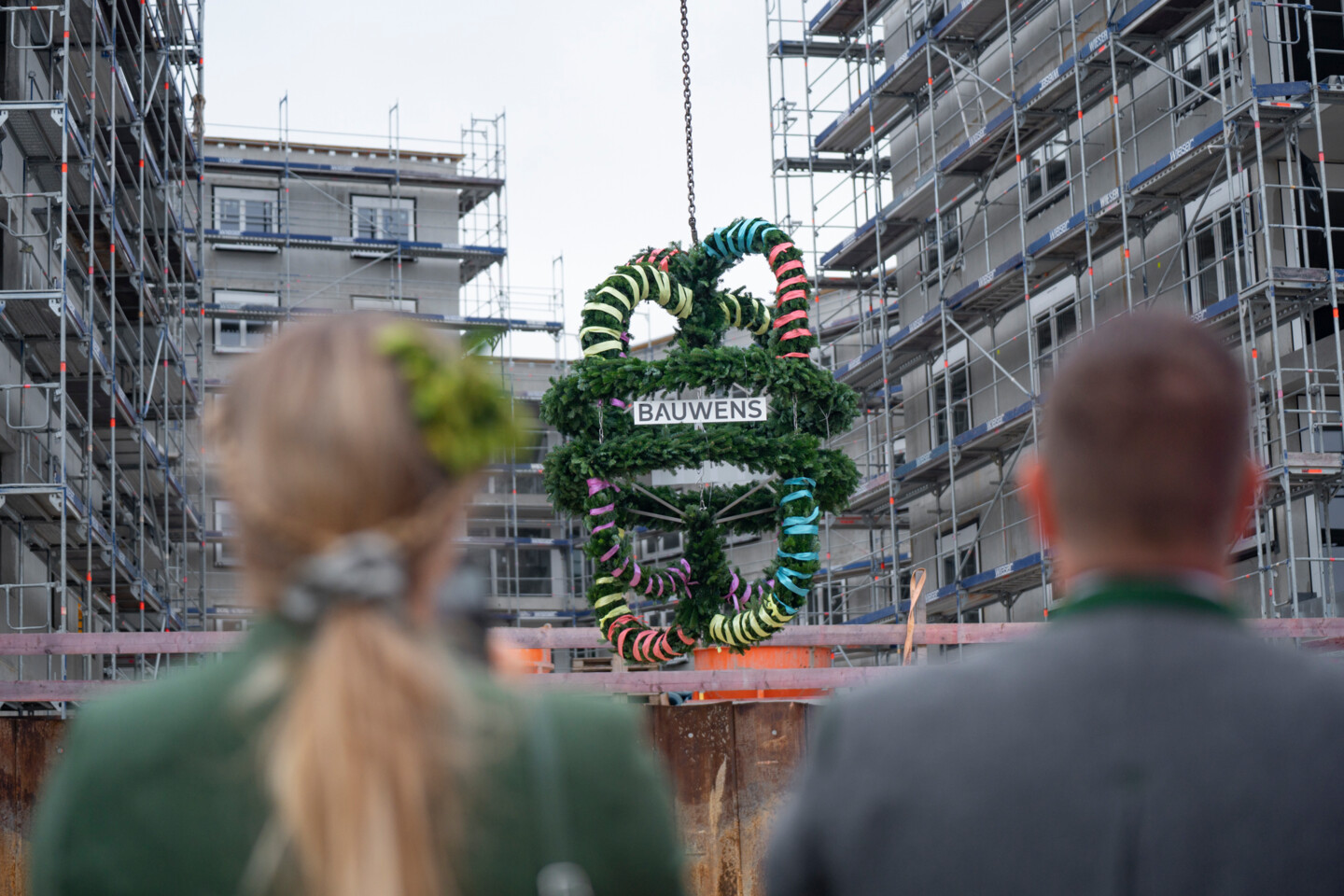 Blick über die Schulter der Gäste auf die Richtkrone. Im Hintergrund die Baustelle.