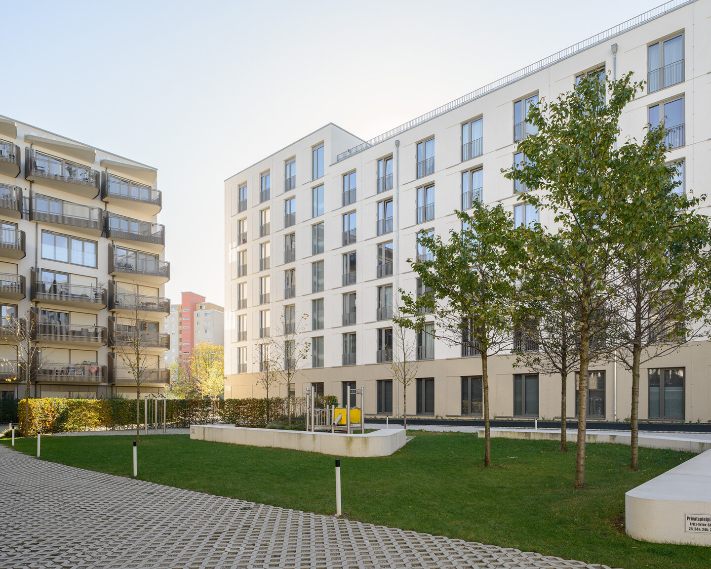 Innenhof des Wohnhauses mit Azubiapartments. Neben großzügigen Rasenflächen sieht man auch Bäume und schön angelegte Gehwege.