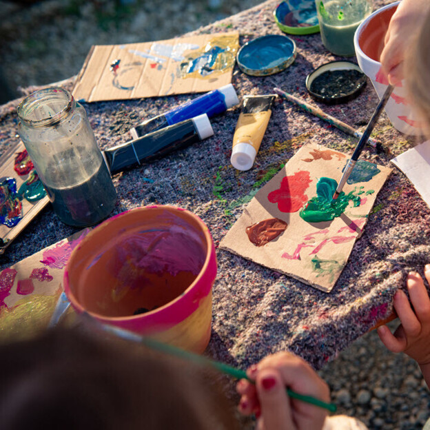 Man sieht zwei Kinder beim Malen mit Wasserfarben.