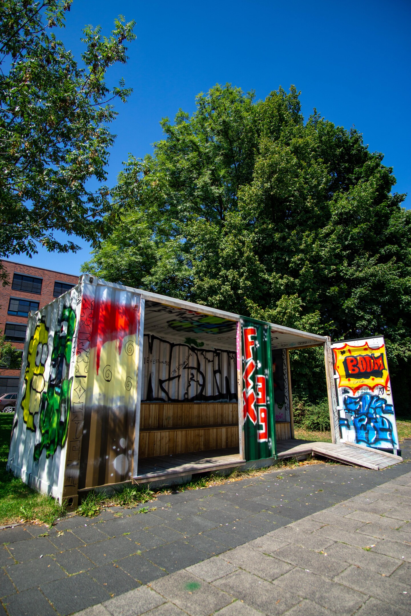 Vorderansicht des Jugendcontainers, der über und über mit buntem Graffiti besprüht ist.