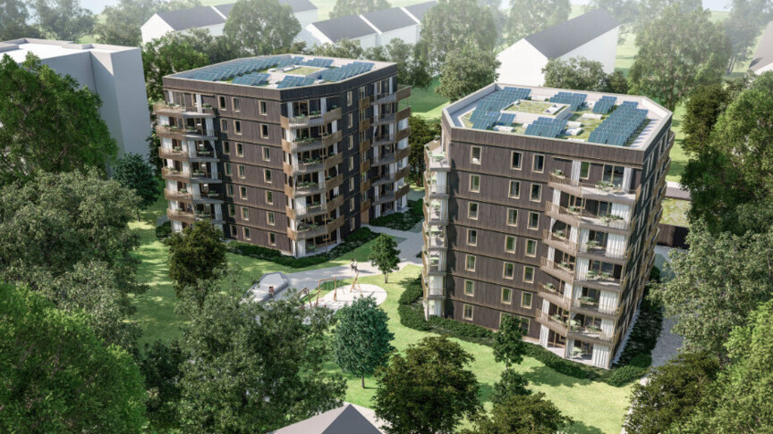 Blick von oben auf zwei mehrstöckige Punkthäuser, die umgeben sind von Bäumen. Dahinter erkennt man weitere Wohngebäude. Der Entwurf zeigt eine Holzfassade mit über Eck liegenden Balkonen und eine Photovoltaikanlage auf dem Dach.