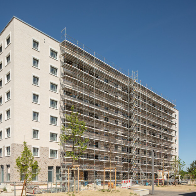 Ansicht Bauprojekt WA12 in neufreimann. Das Gebäude ist schon weitgehend fertig und hat 7 Stockwerke. Das Baugerüst ist zum teil noch vorhanden. Die Grünanlagen noch nicht ganz fertig.