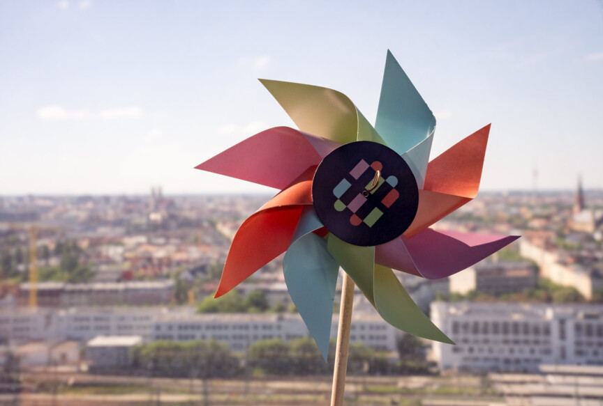 Miniwindrad in den Farben der Münchner Wohnen vor der Stadtkulisse Münchens.