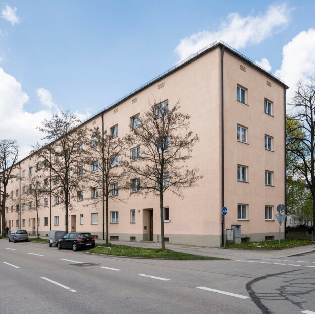 Blick auf einen Gebäuderiegel entlang der Straße.